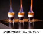 Three shots of flaming B-52 cocktail placed on a bar counter