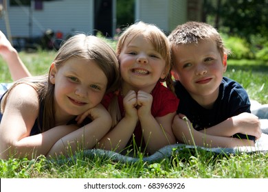 Three Siblings Outside In Grass