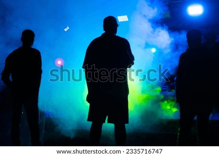 Three silhouetted figures at performance at concert of festival