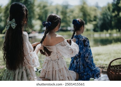 Three sisters enjoy a peaceful afternoon in a park, braiding each other's hair by a tranquil pond, surrounded by lush greenery. - Powered by Shutterstock