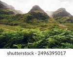 The Three Sisters from within the clouds on the green hills of Glen Coe West Highlands in Scotland, United Kingdom