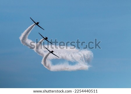 Three of the Skytypers acrobatic airplane performance team perfoming at the Jones Beach Air Show leaving a long smoke trail.