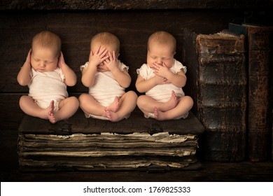 Three Sleeping Newborn Babies Doing The Hear See Speak No Evil Gestures While Sitting On A Stack Of Antique Books (no Triplets, Just 3x Same Baby).