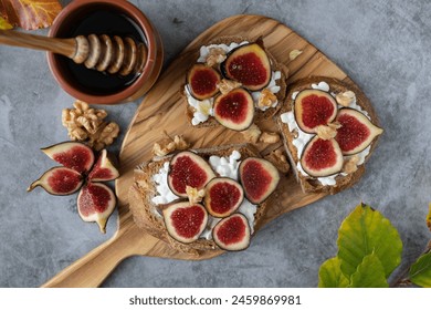 Three slices of bread with figs and cheese on top. A jar of honey is on the table - Powered by Shutterstock