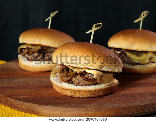 Three slider\
burger with cheese on a rustic\
table