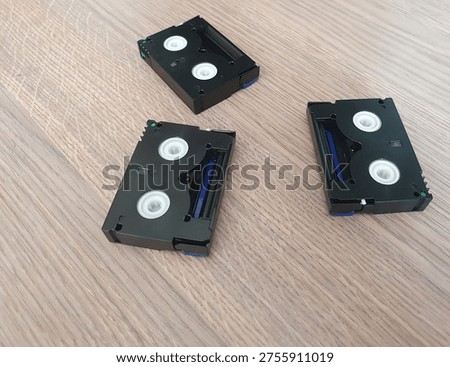 Three small digital video cassettes in MiniDV format on a wooden background. Retro media for video cameras, family video archiving and nostalgia.