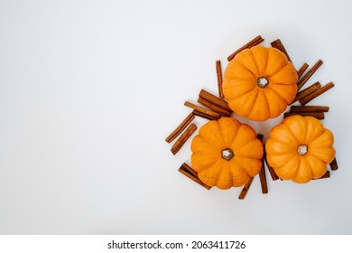 three small orange pumpkins with cinnamon sticks top view flat lay. Halloween and Thanksgiving autumn concept