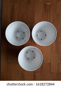 Three small plastic white pots with a brown background.