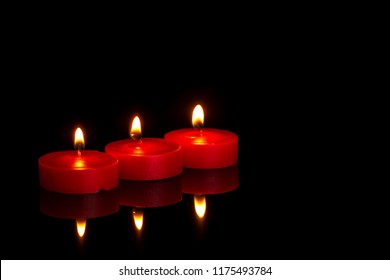 Three Small Red Candles, Tealights, Burning At Night On Black. In Memoriam Or Religious Maybe.