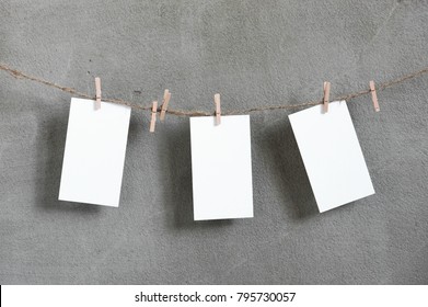 Three small sheets of white paper handing on the rope against concrete wall, copy space  - Shutterstock ID 795730057