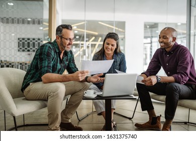 Three Smiling Diverse Business Colleagues Having Casual Sit Down Business Strategy Meeting.