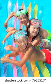 Three, smiling, happy children on a large float in a swimming pool.
