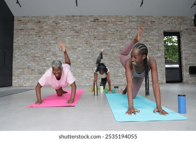 Three smiling women exercising on yoga mats in yoga studio - Powered by Shutterstock