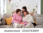 Three smiling women spanning multiple generations celebrate their bond, sharing laughter and hugs in warm and inviting living room. power family support and unity in promoting resilience