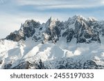 Three snowy mountain peaks in Alps range with blue sky; winter landscape of 3 peaks in French Alps near Mont Blanc and Chamonix with snow and sunshine and trees at the foot of the mountains
