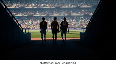 Three soccer players entering soccer field on the professional stadium. They are exiting the shadow. Sunny weather. Animated crowd.