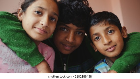 Three South Asian Kids Hugging Each Other  And Looking At The Camera