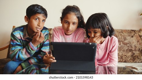 Three South Asian Kids Sitting Together In Front Of A Tablet