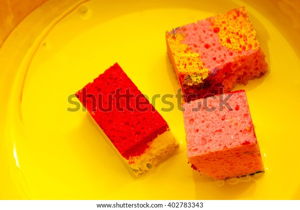 three sponges with yellow paint in a bowl