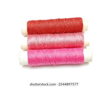 Three spools of sewing thread—terracotta, pink, and fuschia—are placed against a white background.