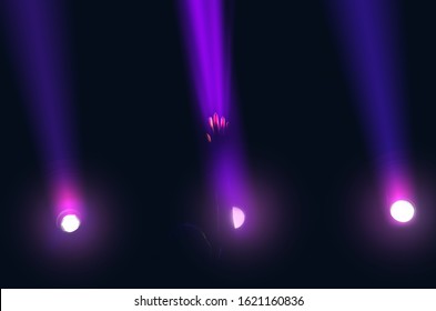 Three Spotlights Shine Brightly In Sky. The Girl Raised Her Hand And Touched A Ray Of Light With Her Fingertips, Dark Background.