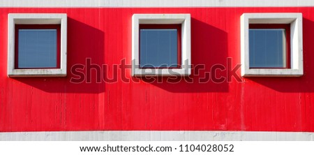 three square windows in the building with red wall