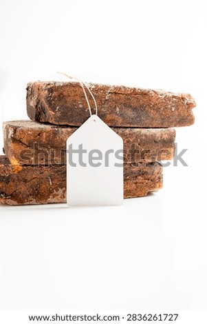 Three stacked rustic, weathered bricks on a white background with a blank white tag. Mockup or Copyspace