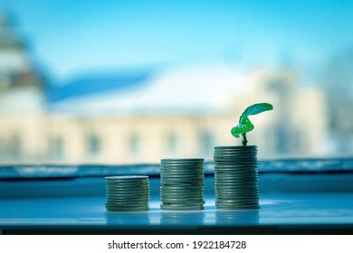 Three stacks of coins in the form of steps, on the last one there is a green sprout. Business development concept