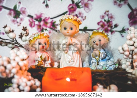 Three statues of angels. Children of angels are praying by the candle.