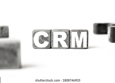 Three Stone Cubes Inscribed With The Word CRM Customer Relationship Management Among The Cubes On A White Background. Strong Business Concept