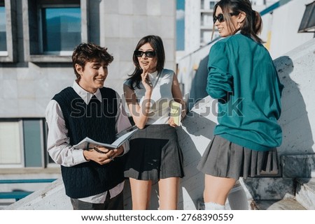 Three students chat and review notes while standing on a rooftop near campus buildings. The friends laugh and study together outdoors in casual school outfits, students.