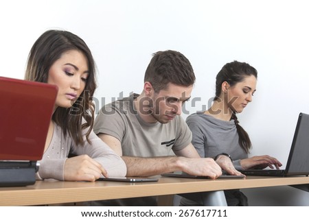 Three students learning with laptops and tablets