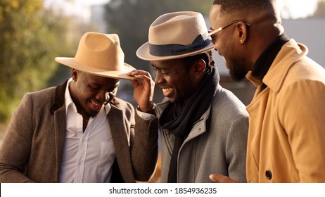 Three Stylish African Friends In Hats Talks In A City Street