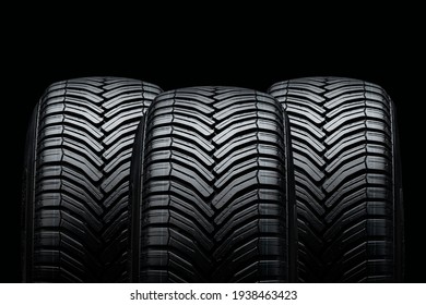 three summer tires on a black background. Drainage grooves and slats