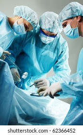 Three Surgeons Busy With A Patient