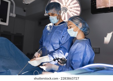 Three surgeons doing laparoscopic surgery. Doctors looking at image on monitor. Medicine and healthcare concept. Internal organ of patient seen on computer monitor - Powered by Shutterstock