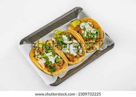Three tacos on white paper on black tray with lengua meat