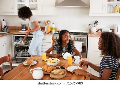 Three Teenage Girls Clearing Table After Family Breakfast - Powered by Shutterstock