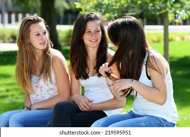 Three Teenage Girls Talking, Sitting On A Bench