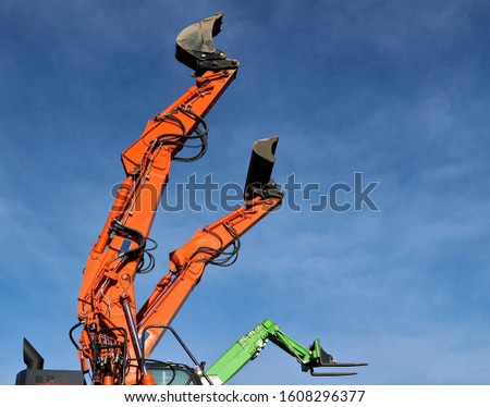 Three telescopic handler booms raising in the air with different attachment mounted to the end: two kind of shovels and one forklift.