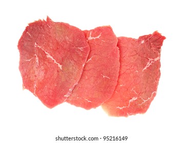 Three Thin Slices Of Fresh Beef Eye Round Steak On A White Background.