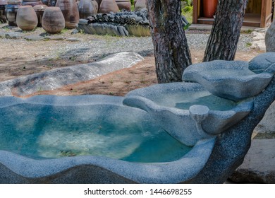 Three Tiered Water Basin And Fountain In Shade Of Tree Located At Mountainside Buddhist Temple.