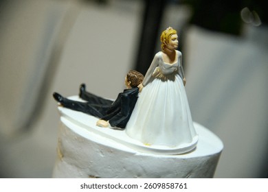 Three tiered white rustic looking wedding cake. Decorated with roses with humorous figures of newlyweds on top