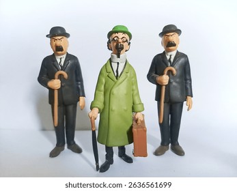 Three Tintin figurines, including Professor Calculus and two men with moustaches, stand against a white background