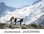 Three tourists having fun and posing for the camera. Snow-capped mountain in the background.  Mount Rainier National Park in summer. Washington State.