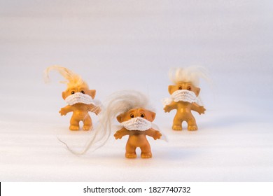Three toy trolls wearing masks against white background