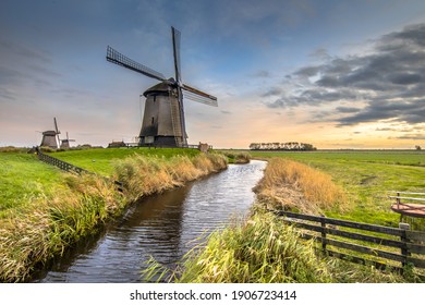 Three Traditional wooden windmills along canal in old agricultural landscape near Schermerhorn, North Holland. Netherlands