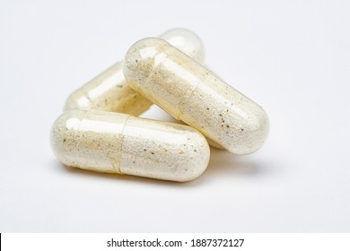 three transparent pill, with white and black specs ingredients, against a white background