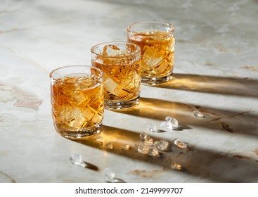 Three transparent shorts of whiskey on the table making sun reflection. - Powered by Shutterstock