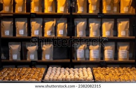 Three trays of assorted pine nut panellets and coconut sweets and toasted cream fresh from the gourmet artisan oven with jars and sacks of ingredients and flour in the background. Typical artisan.